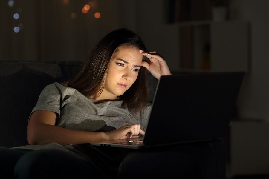 Worried woman using a laptop in the night