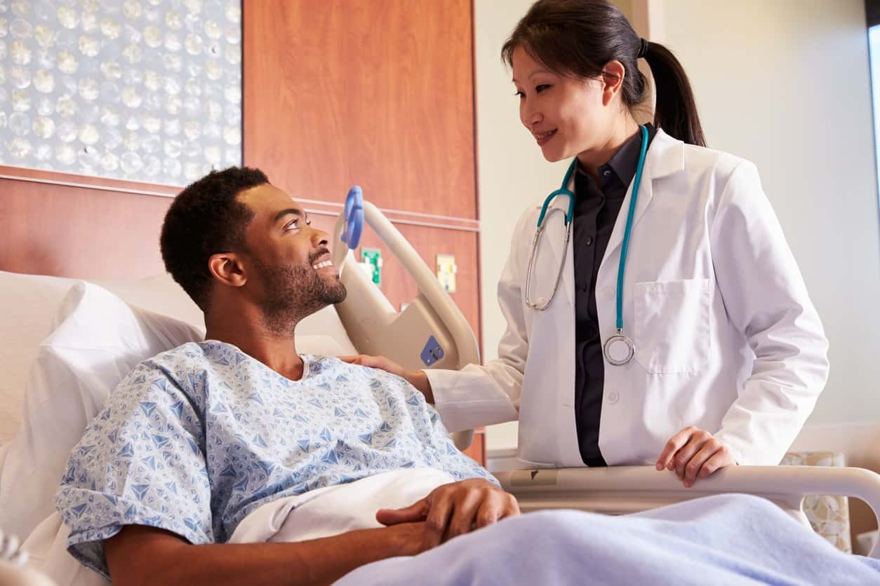 Female Doctor Talking To Male Patient In Hospital Bed Regional One Health